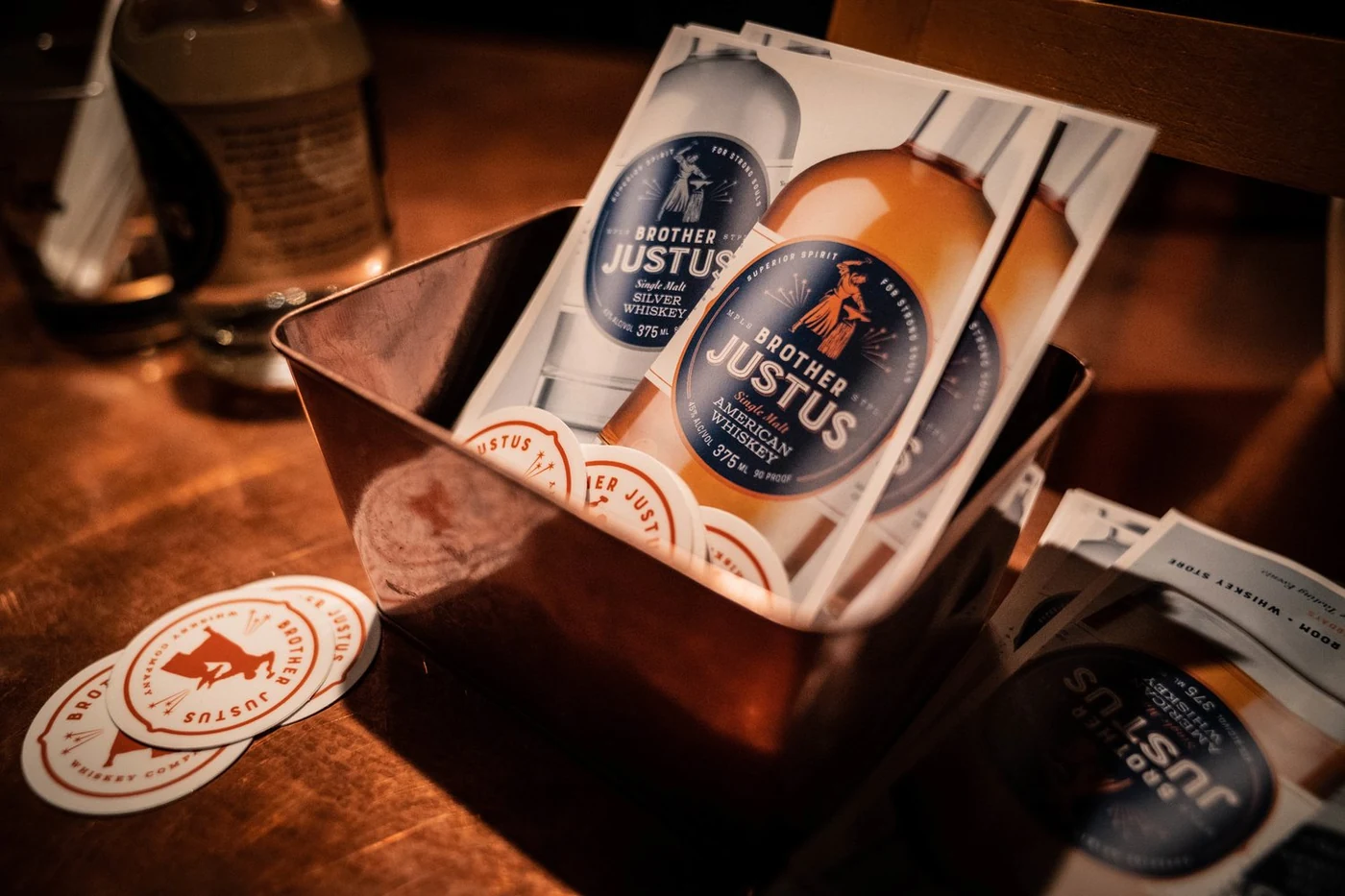 Brother Justus printed marketing materials and branded coasters in a copper tin
